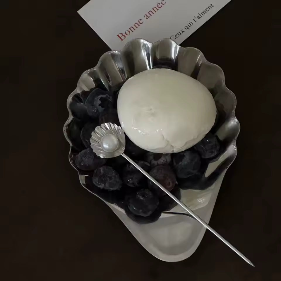 Decorative brooch with a white sphere, blueberries, and a pearl on a dark background