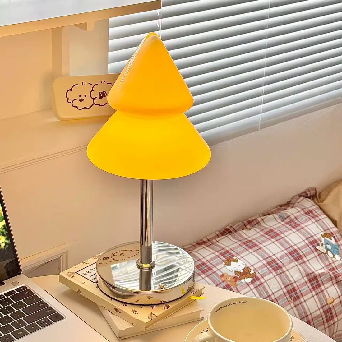 Green lamp shaped like a Christmas tree on a table with a mug and newspaper.