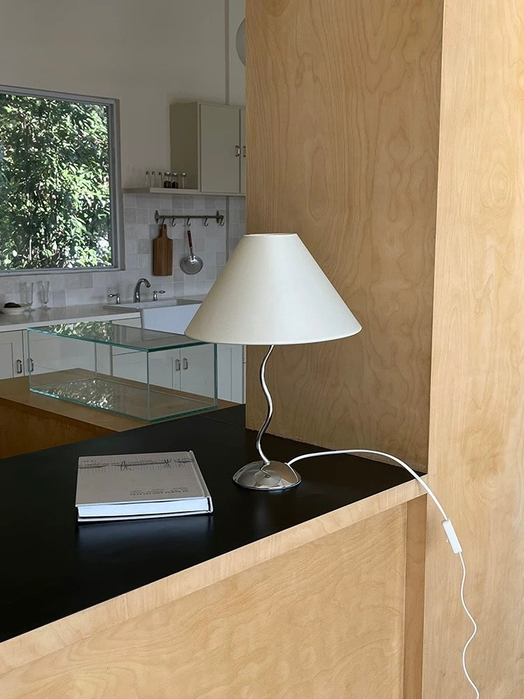Modern kitchen with a lamp on a counter and a view of trees outside.