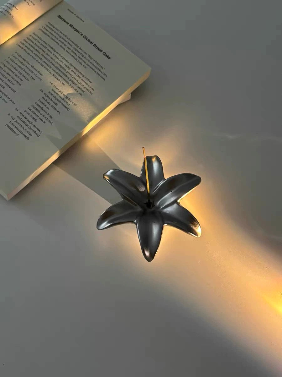 Decorative black wall light fixture casting a warm glow on a white wall.