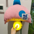 Plush toy with a striped pattern and blue accents, held by a hand, against a neutral background.