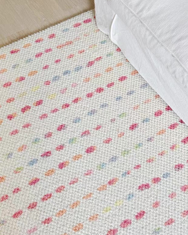 Floral patterned rug on a wooden floor with a white baseboard.