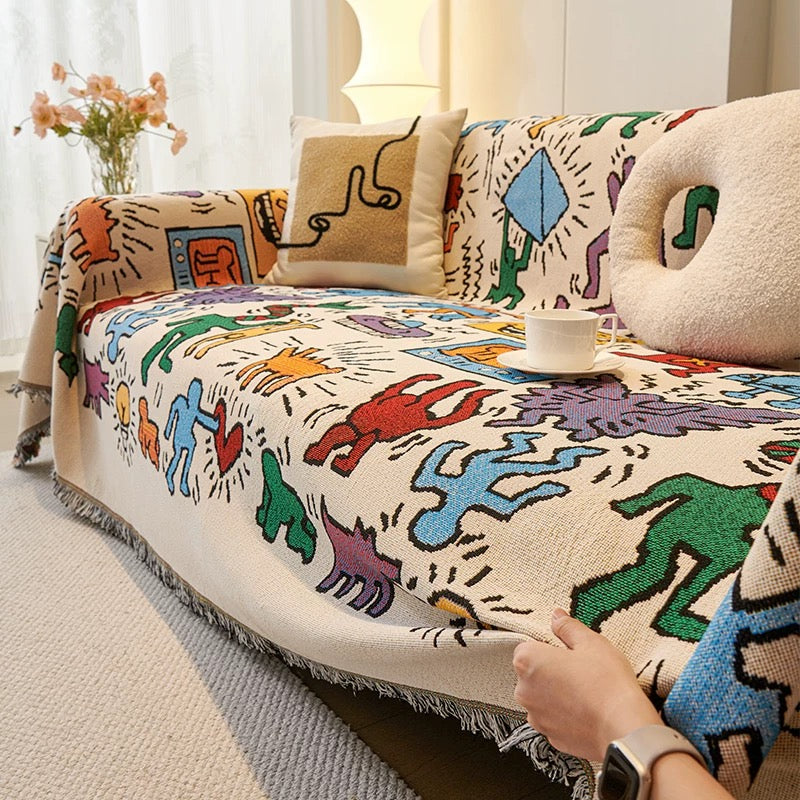 Cotton throw with tribal-style figures spread across a bed