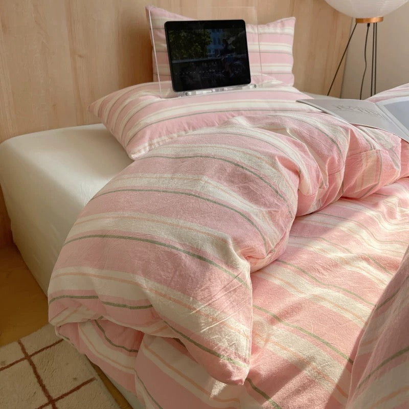 Bed with pink and white striped bedding and a tablet on a pillow.