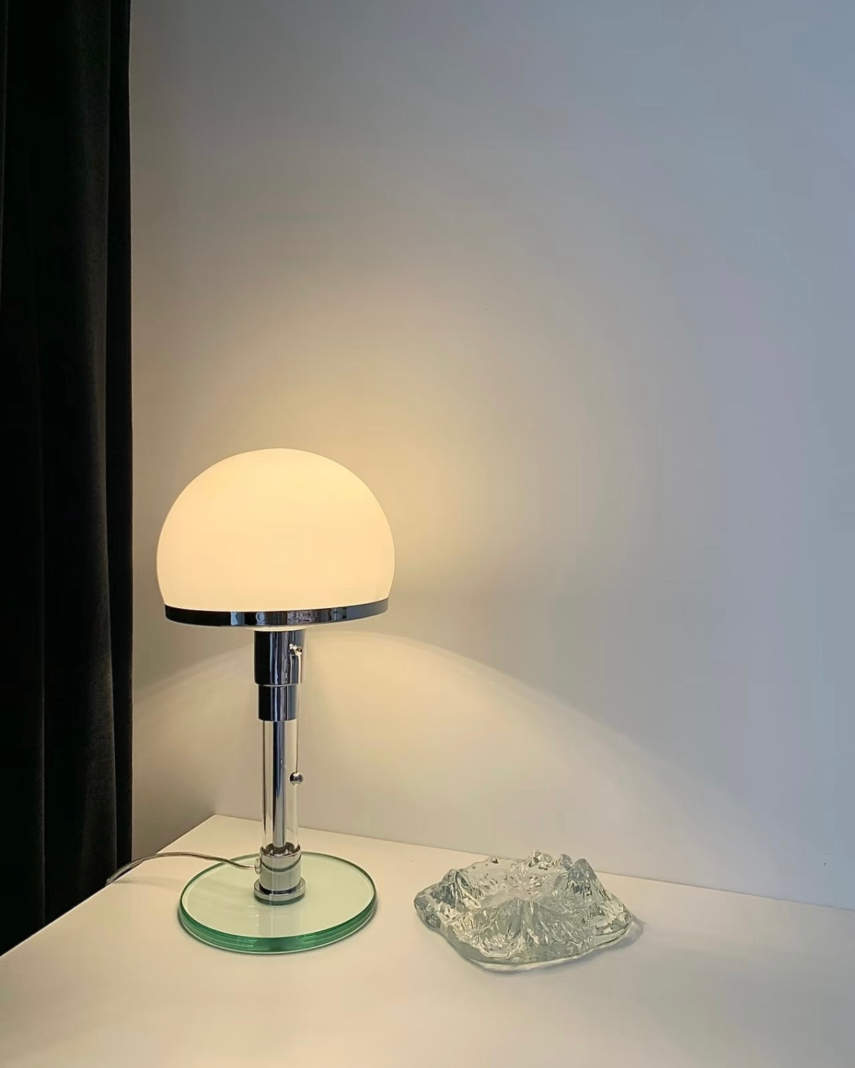 Soft glow mushroom lamp placed on white tabletop with open magazine and neutral room decor.