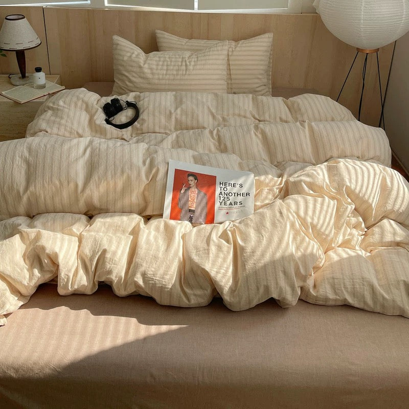 Beige comforter on a bed with pillows and a magazine titled 'Here's to Another Year'.