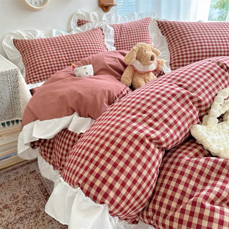 Red and white checkered bedding set on a bed with a teddy bear.