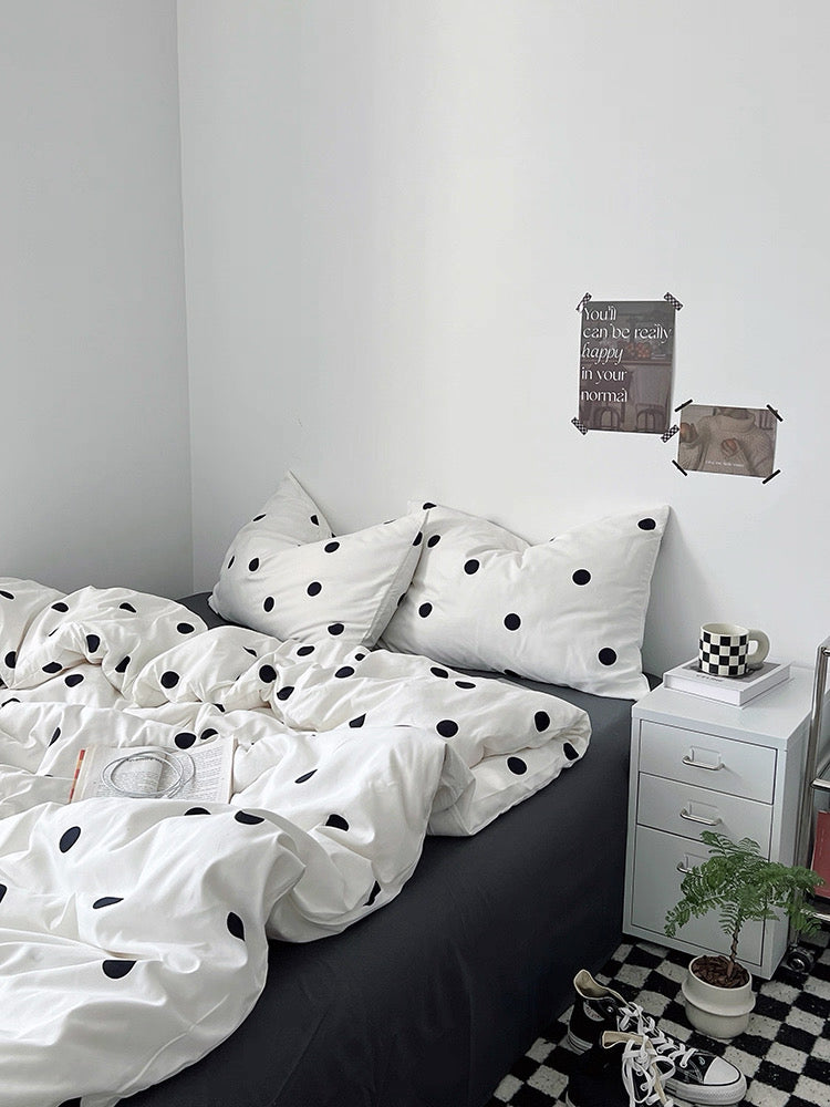 Bedroom with polka dot bedding and a nightstand.