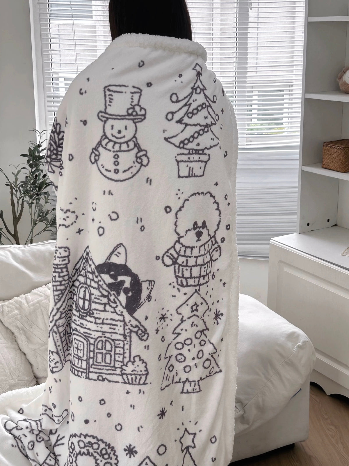 Black and white Christmas blanket held up to show the full snowy holiday print