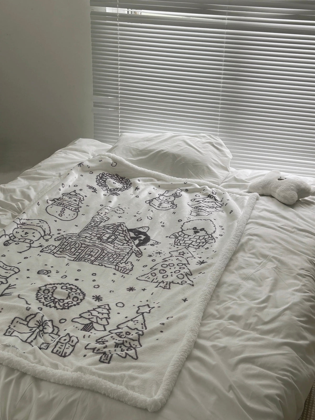 Black and white Christmas sherpa blanket folded across a white bed