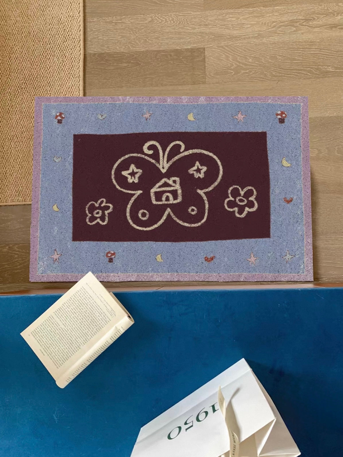 A blue butterfly living room rug has a burgundy center, pale outline artwork and a lilac outer edge.