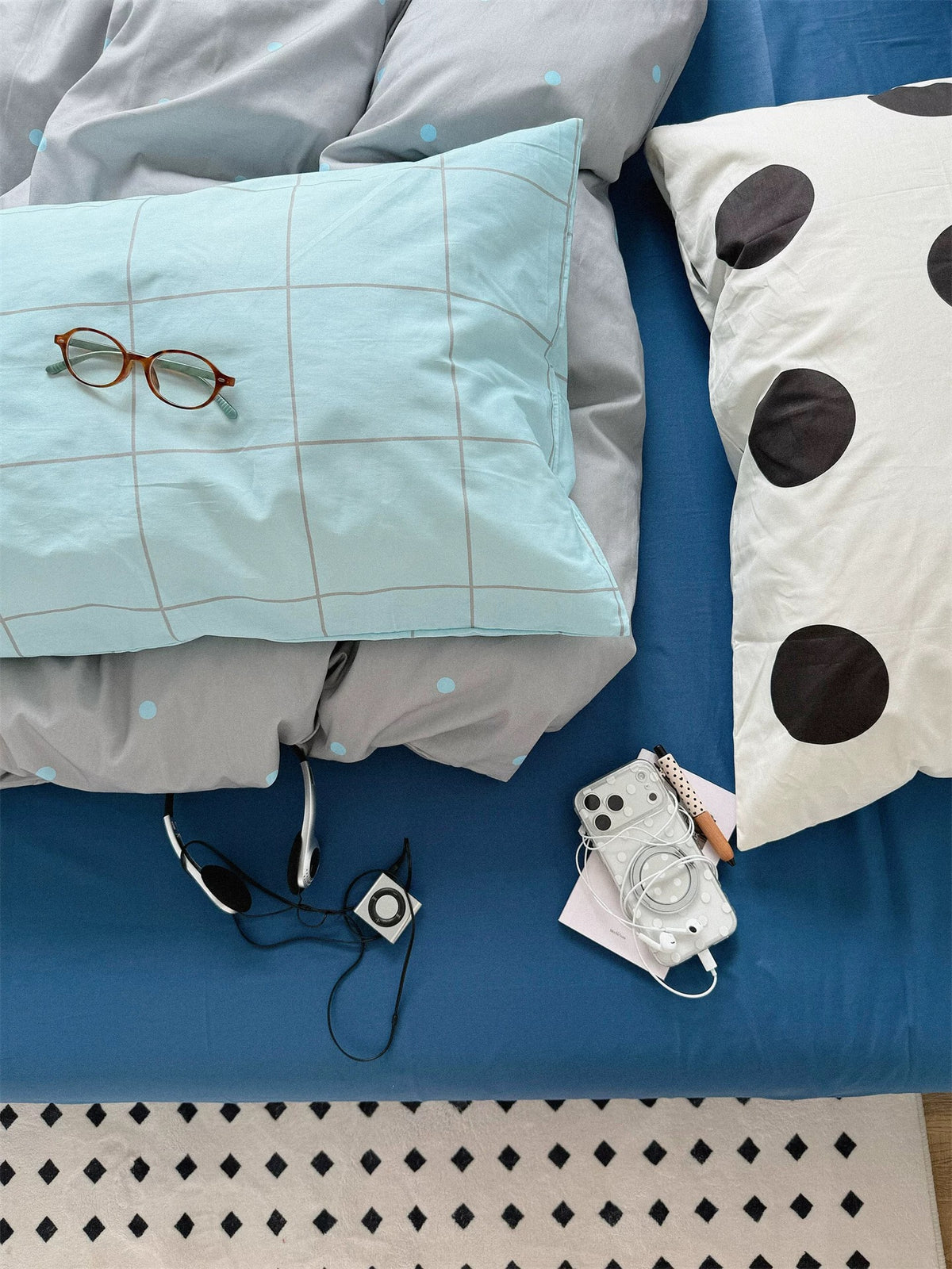 Close view of a blue check pillowcase and a large black dot pillowcase on the blue sheet.