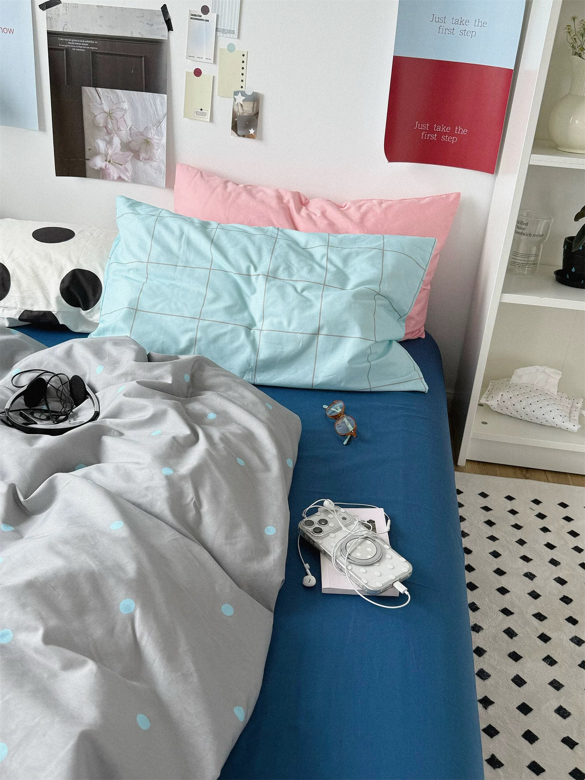 Blue flat sheet beside the gray dotted cover with blue check and pink pillowcases.
