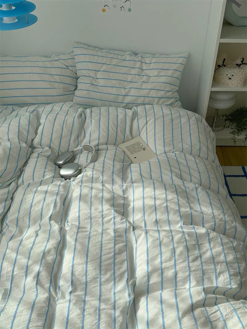 Striped bedding on a bed with a white wall and shelf in the background