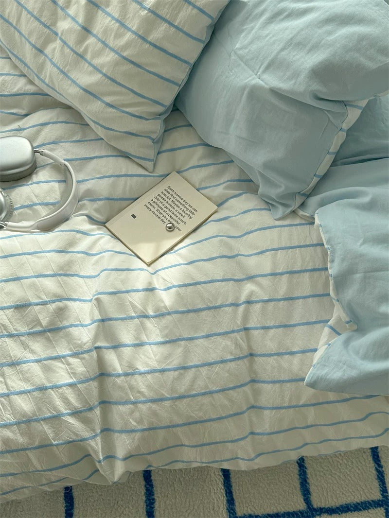 Blue striped cotton bedding set styled in clean Korean minimal bedroom with natural daylight and soft textures