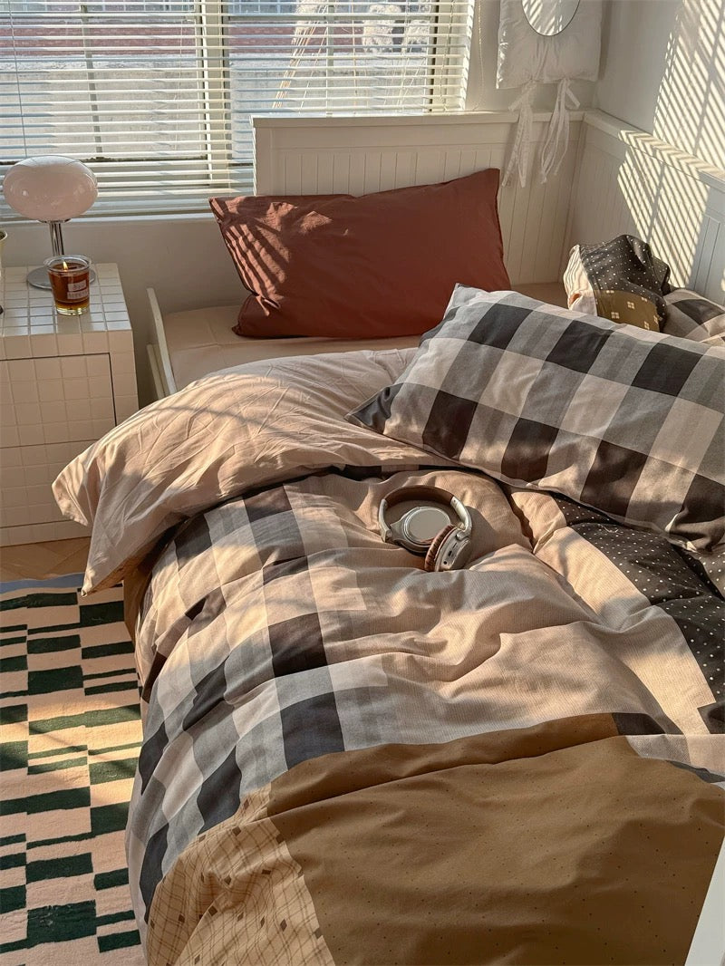 Bedroom with plaid bedding and a window with blinds.