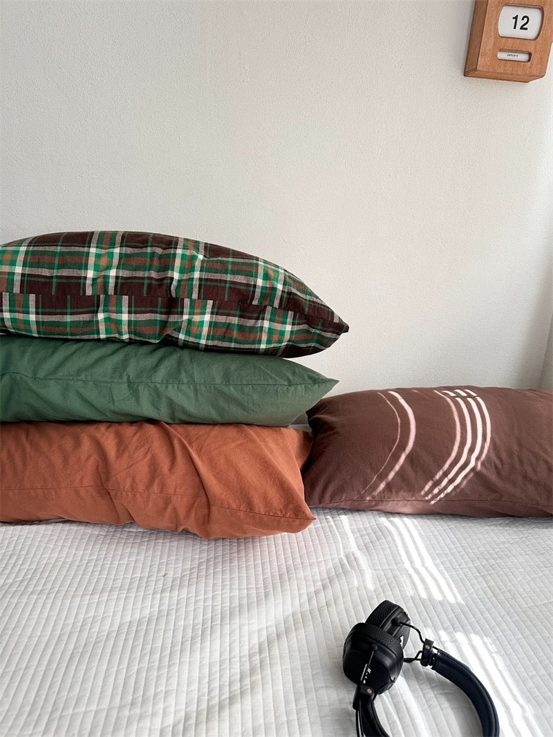 Brown and green plaid pillowcases sit among plain green, rust orange and cocoa brown designs.