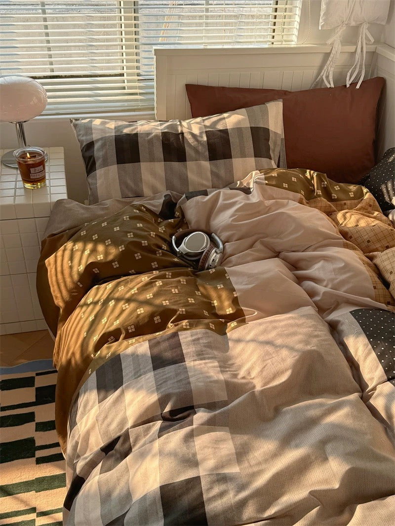 Bedroom with checkered bedding and pillows, a glass of beer on a nightstand.