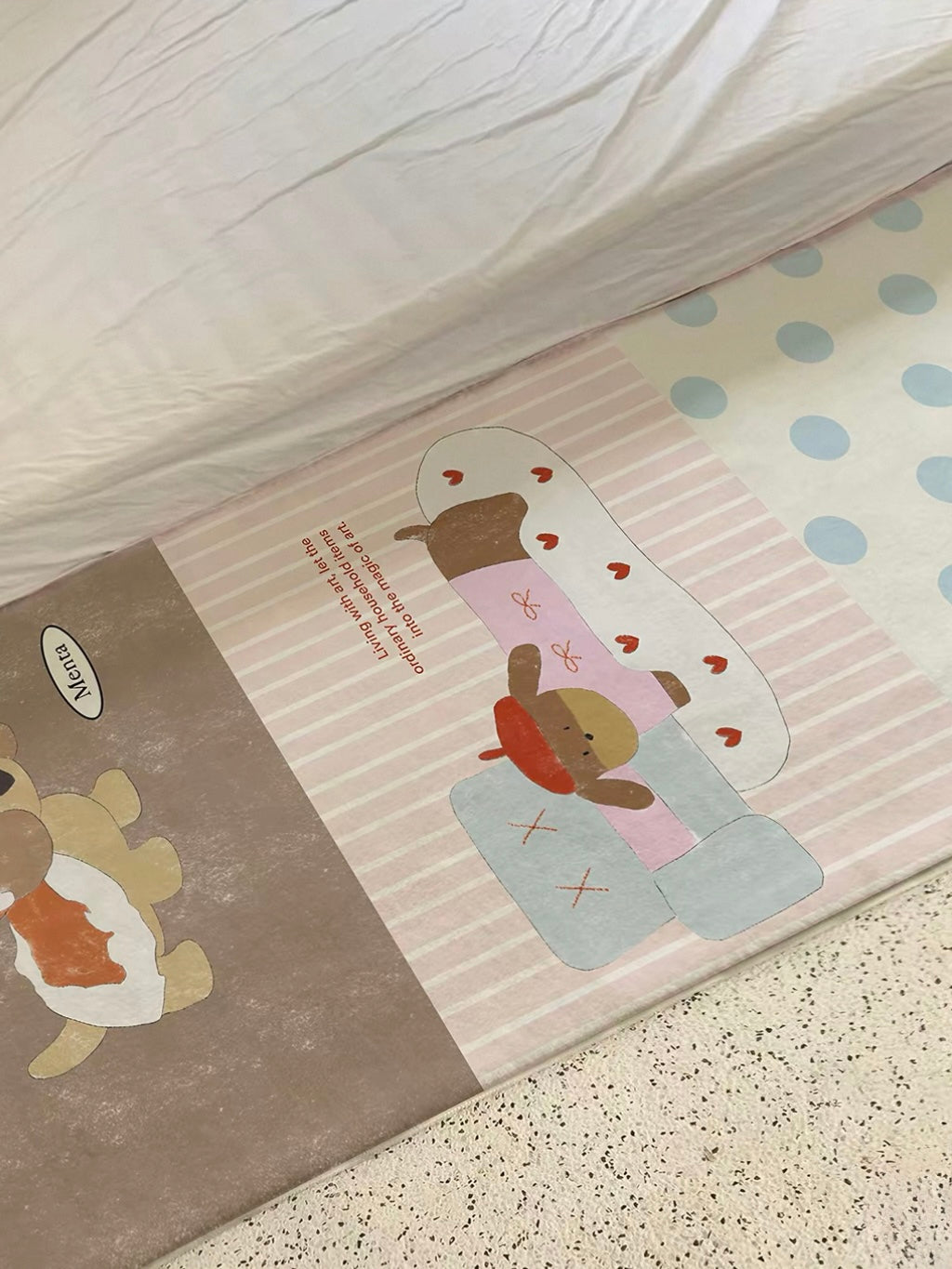 A brown cartoon dog rug with pale striped and blue dotted panels lies at an angle beside a bed.