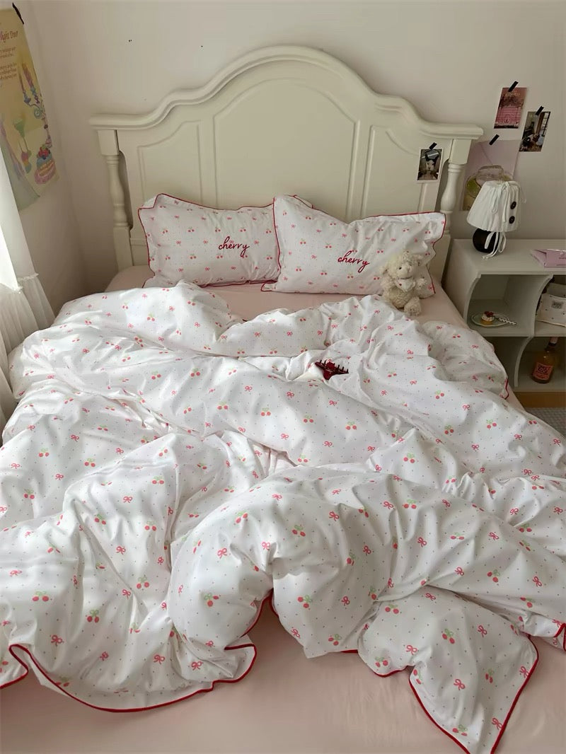 White bedspread with red floral patterns on a bed in a bedroom.