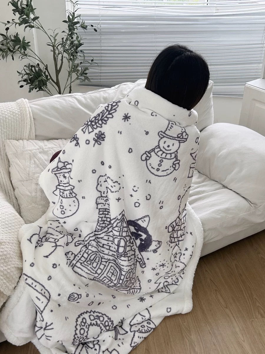 White Christmas fleece blanket wrapped around a person on a sofa