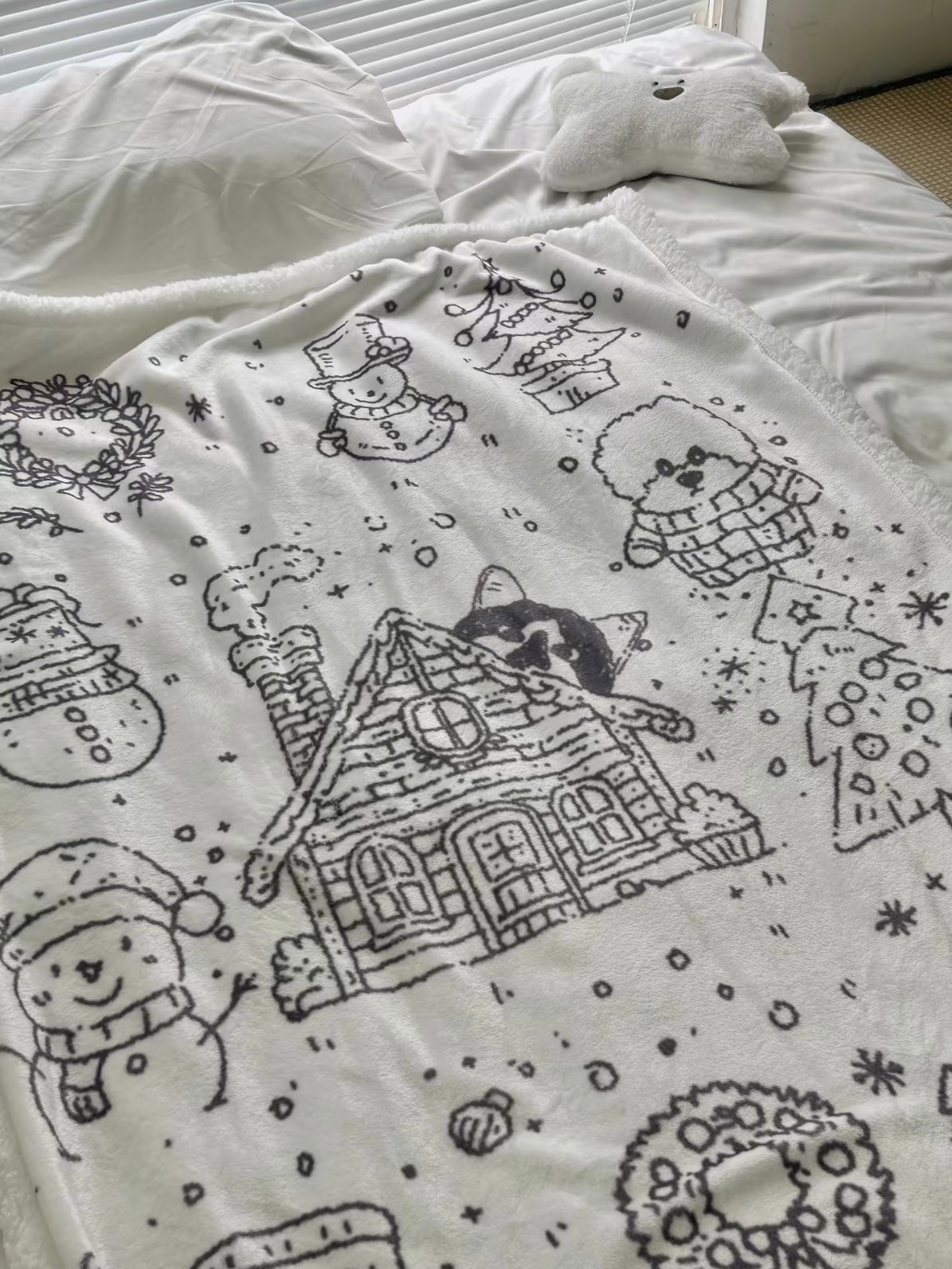 Black and white Christmas throw blanket draped across white bedding