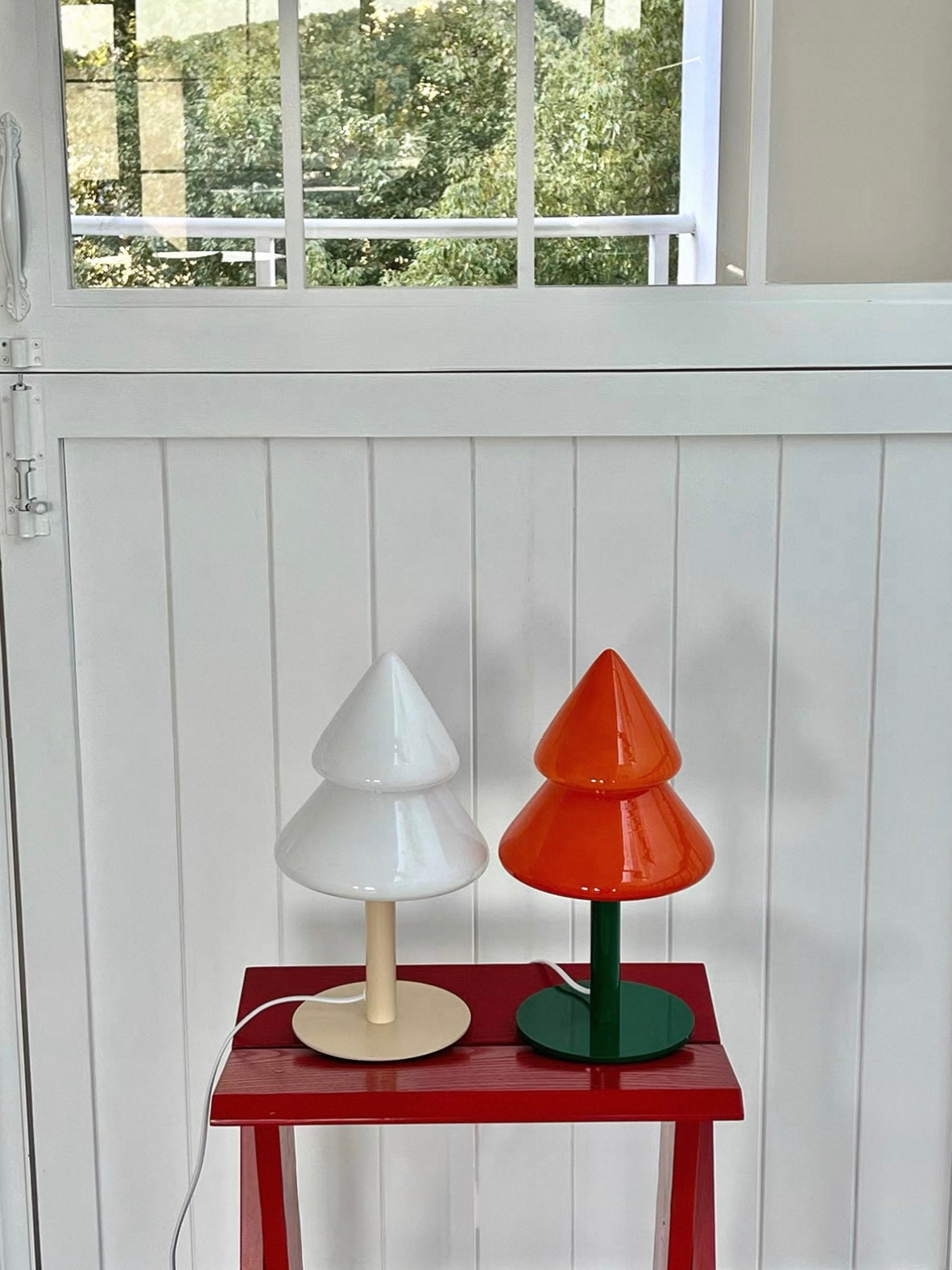 Blue and orange Christmas tree desk lamps displayed on a red side table