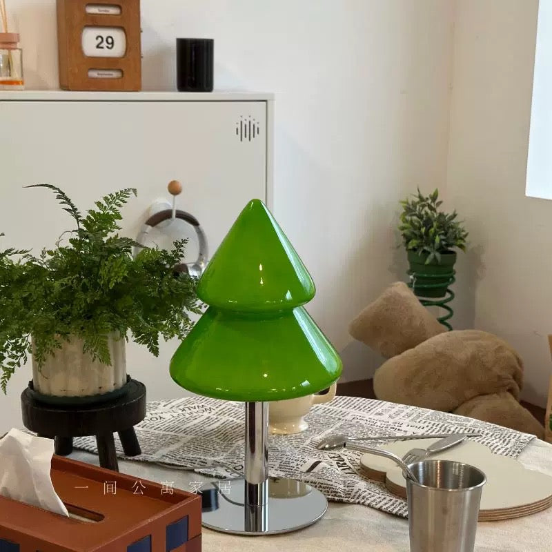 Green lamp on a table with plants and decor items in the background