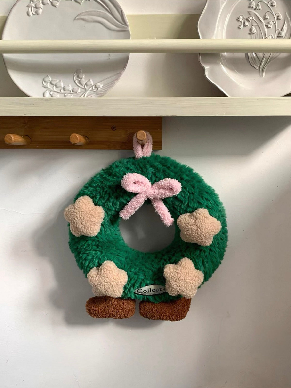Christmas wreath pillow with beige plush stars and a pink bow displayed on a shelf