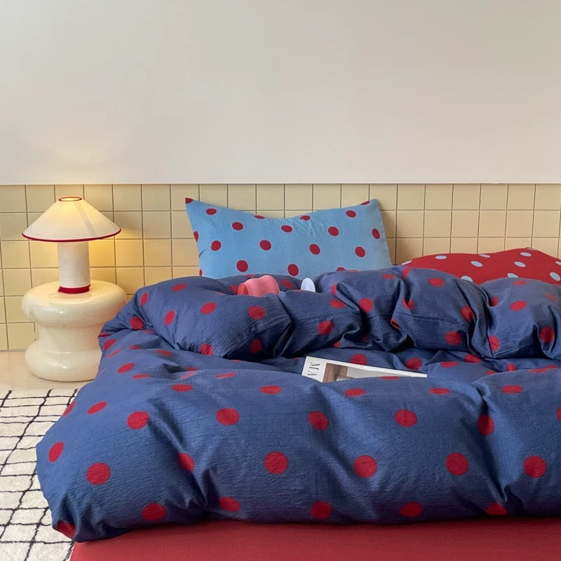 College dorm room styled with navy polka dot bedding and playful red accents