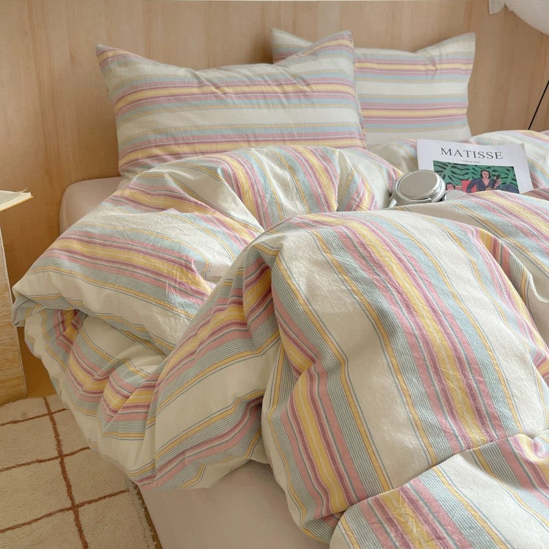 Striped bedding set on a bed with a side table and book in the background.