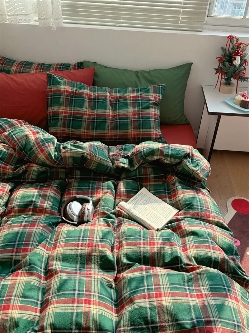Plaid-patterned sofa with cushions and a blanket in a room with a small table and decorative items.