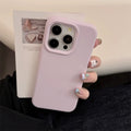 Person holding a phone with a pink case, blurred magazine in the background