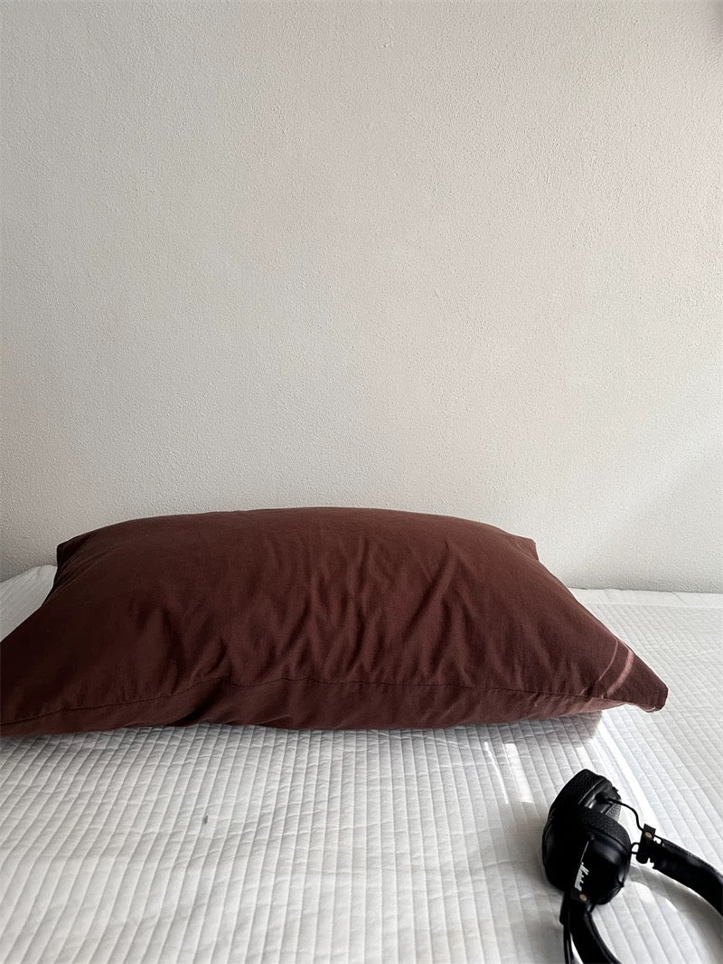 A cocoa brown pillowcase lies on its own with visible fabric folds.