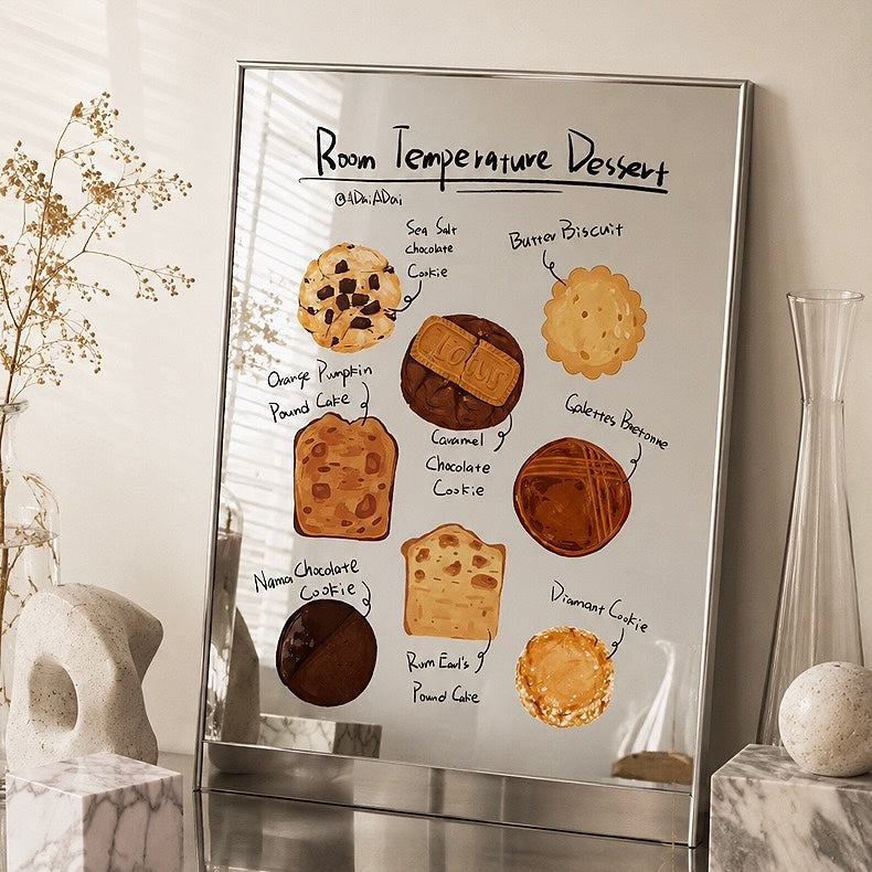 A framed wall art print featuring a whimsical dessert-themed poster titled 'Room Temperature Dessert' hangs on a beige wall in a styled room. The poster shows illustrated baked goods like cookies, cakes, and pastries with handwritten labels.