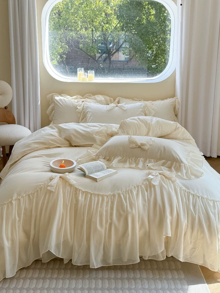 Neatly made bed with white bedding in a room with a window view of greenery.