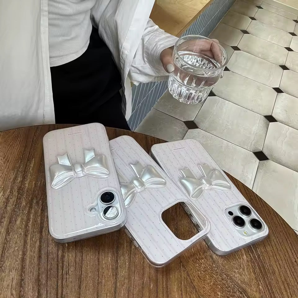 Phone case with a bow design held by a hand against a neutral background