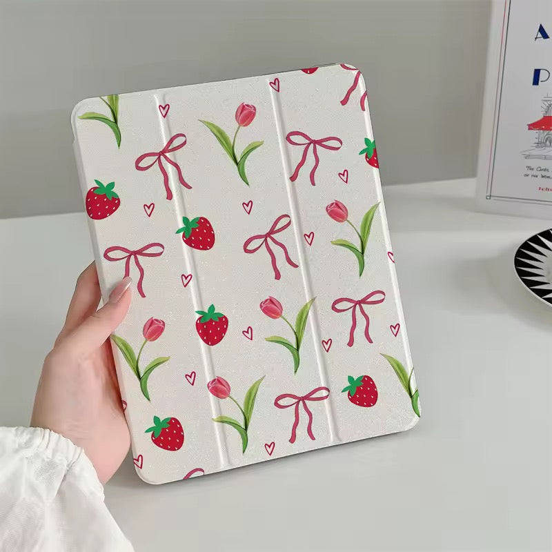 White tablet case with strawberry, tulip, and bow pattern held by a hand on a light gray background.