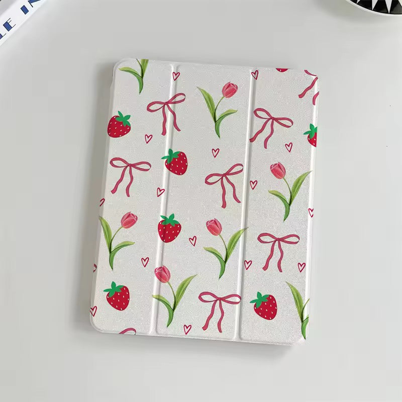White tablet case with strawberry, tulip, and bow pattern held by a hand on a light gray background.