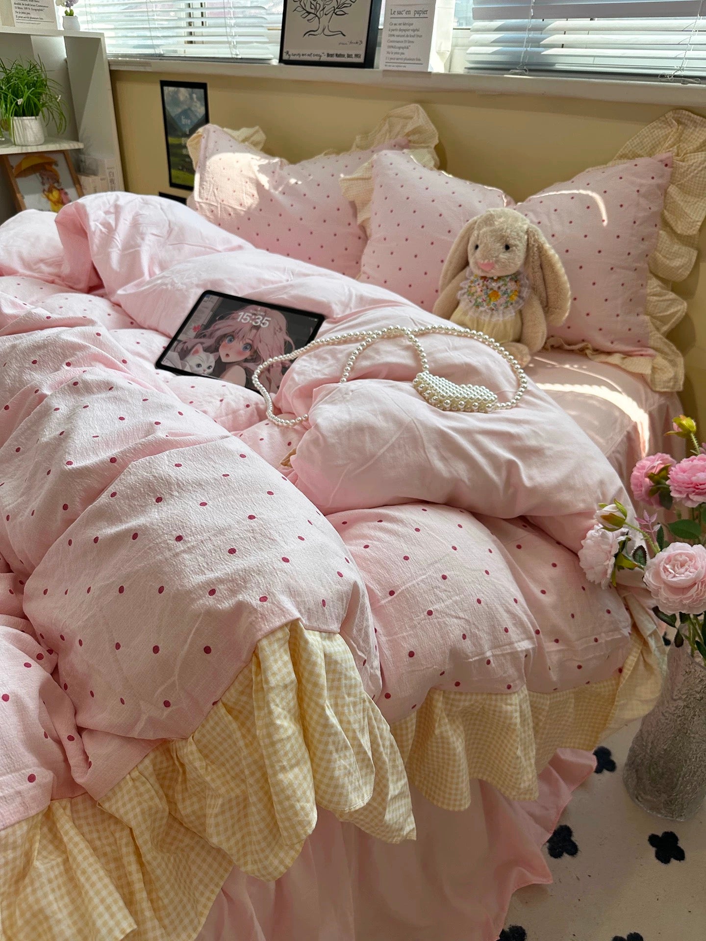 Pink and yellow bedding set with a teddy bear and decorative pillows on a bed.