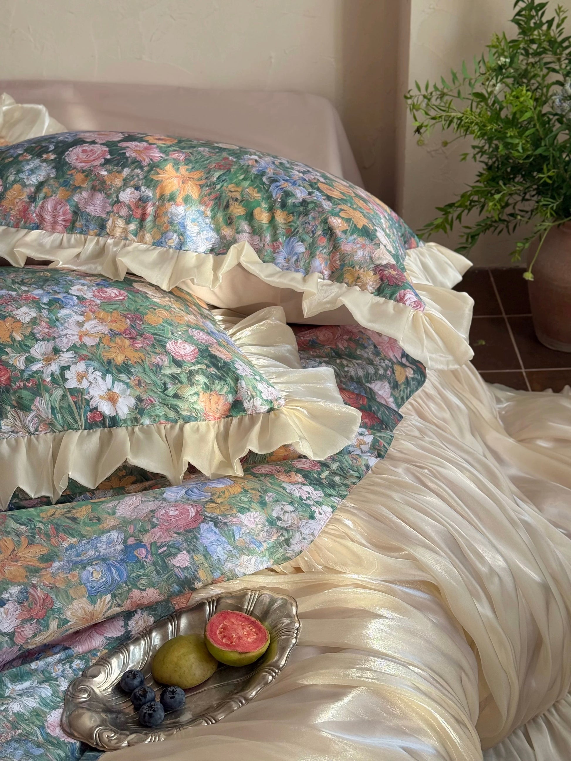 Floral-patterned bedspread with ruffles on a bed in a room with a plant.