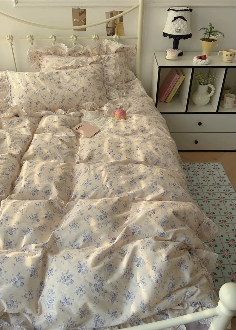 Floral patterned comforter on a bed in a bedroom with a shelf in the background.
