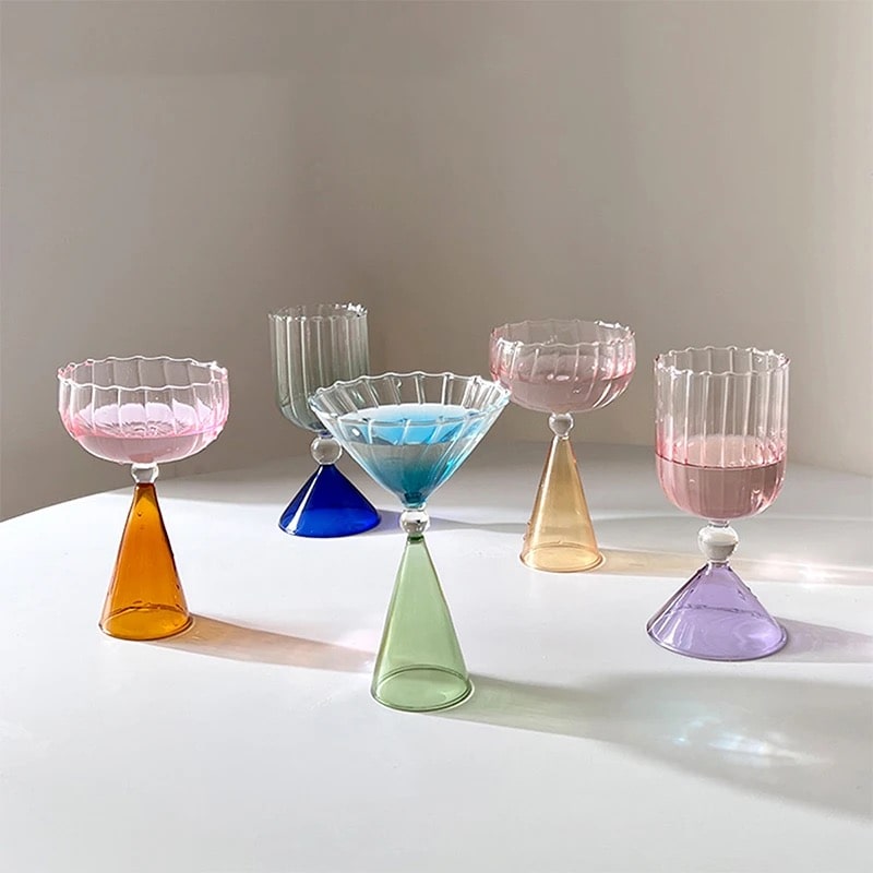 Colorful coupe cocktail glass with rounded bowl, gold rim, and decorative multicolor stem detail shown.
