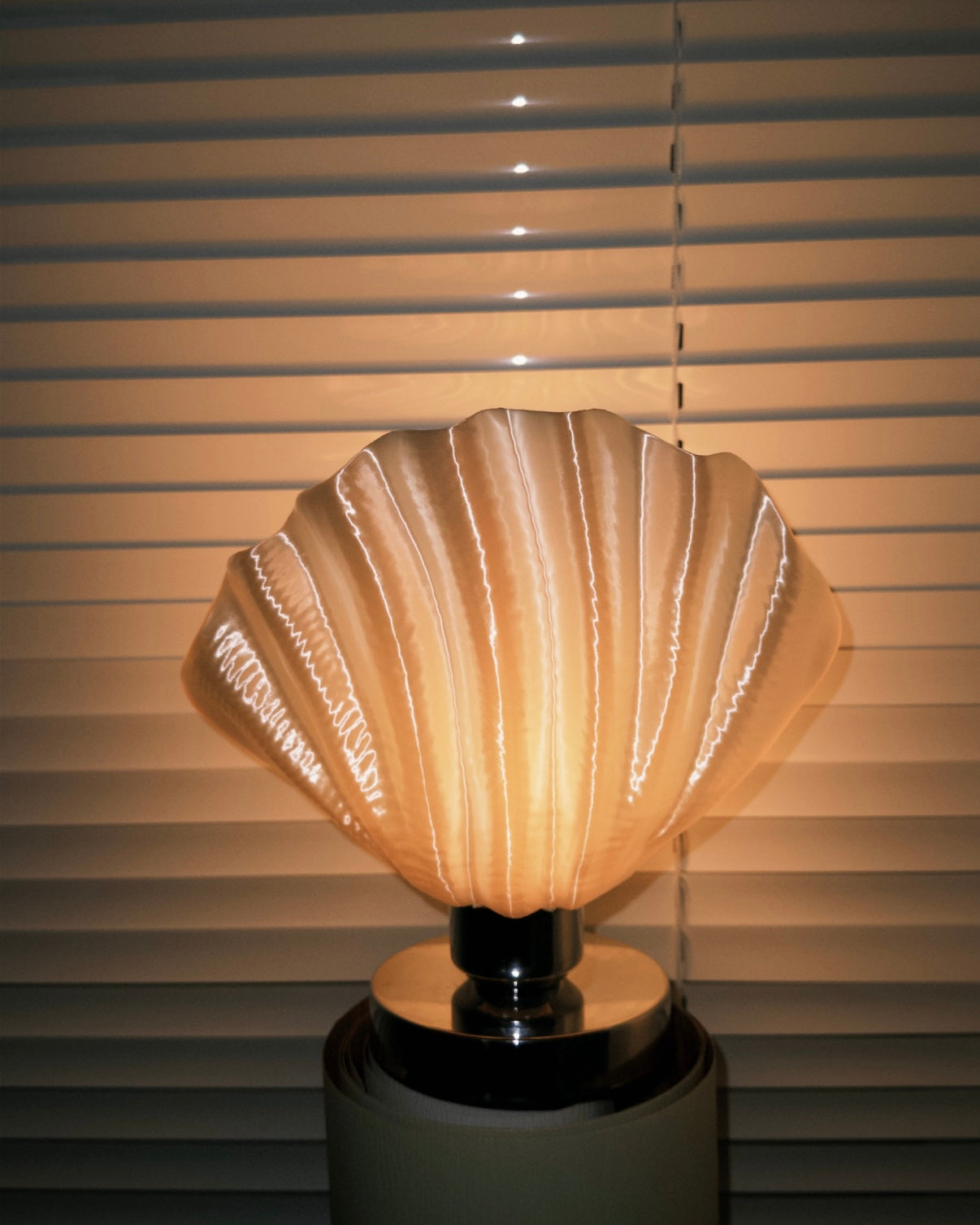 Decorative shell table lamp providing soft ambient lighting for cozy bedroom reading corner