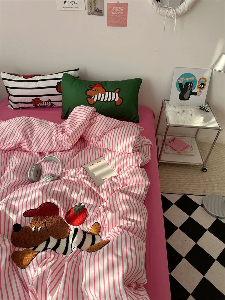 Bed with pink and white striped bedding featuring cartoon characters, next to a small table with decorative items.