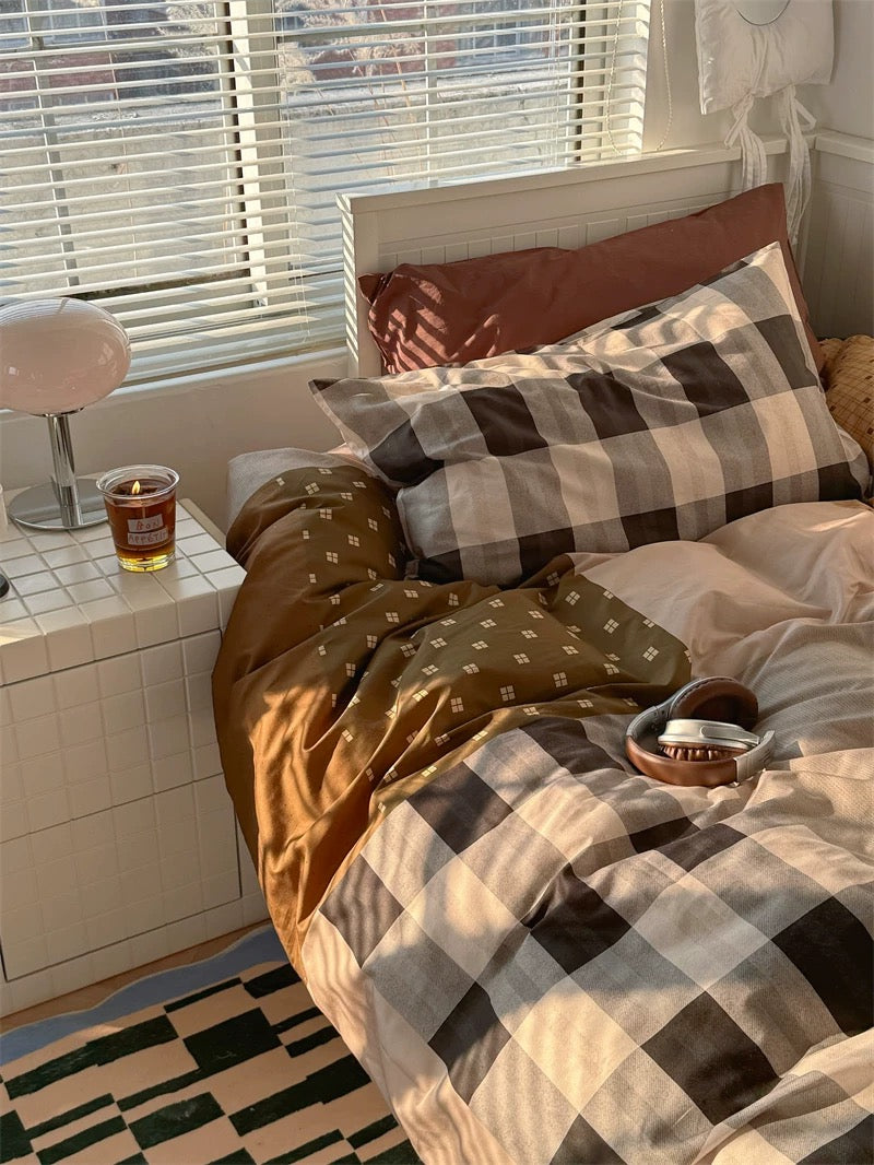 Bedroom with checkered bedding and a glass of beer on a nightstand.
