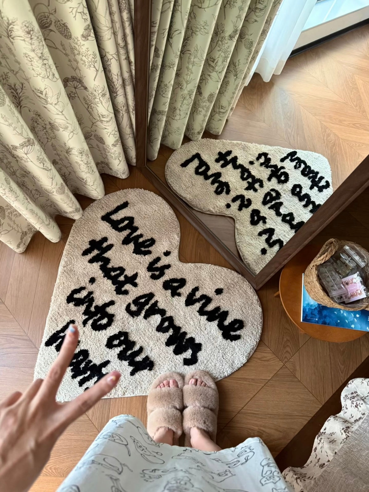 Cream heart rug with black lettering lies beside a floor mirror, showing the heart outline and its reflection.