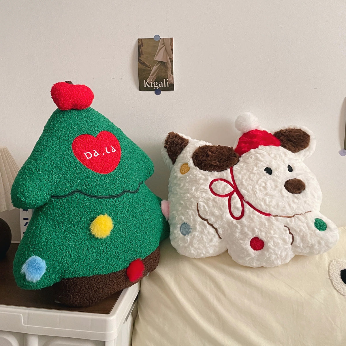 Green Christmas tree pillow and white Christmas dog cushion displayed together on a bed