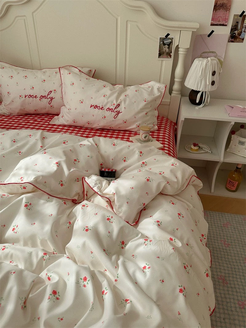 Bedroom with white bedding featuring red floral patterns and 'love only' text on pillows.