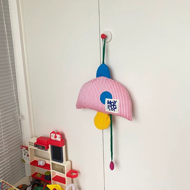 Colorful children's toy organizer hanging on a white door with toys on the floor below.